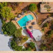 Drohnenaufnahme des Manta Resorts auf Pemba Island mit Poolanlage, Sonnenliegen, tropischer Vegetation und direktem Zugang zum weißen Sandstrand – exklusives Strandresort in Tansania