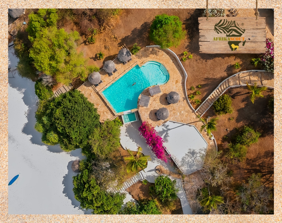 Drohnenaufnahme des Manta Resorts auf Pemba Island mit Poolanlage, Sonnenliegen, tropischer Vegetation und direktem Zugang zum weißen Sandstrand – exklusives Strandresort in Tansania